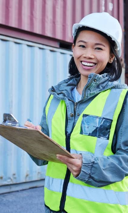 Ingeniera de calidad revisando documentación junto a contenedores de importación